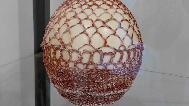 Œuf d'autruche réalisé pour une exposition à la galerie lierman à Liège en 2021. Exposition au profit de la recherche contre le cancer. Œuf d'autruche habillé de fil fait à partir de papier d'emballage camembert. crochet et point loop à l'aiguille